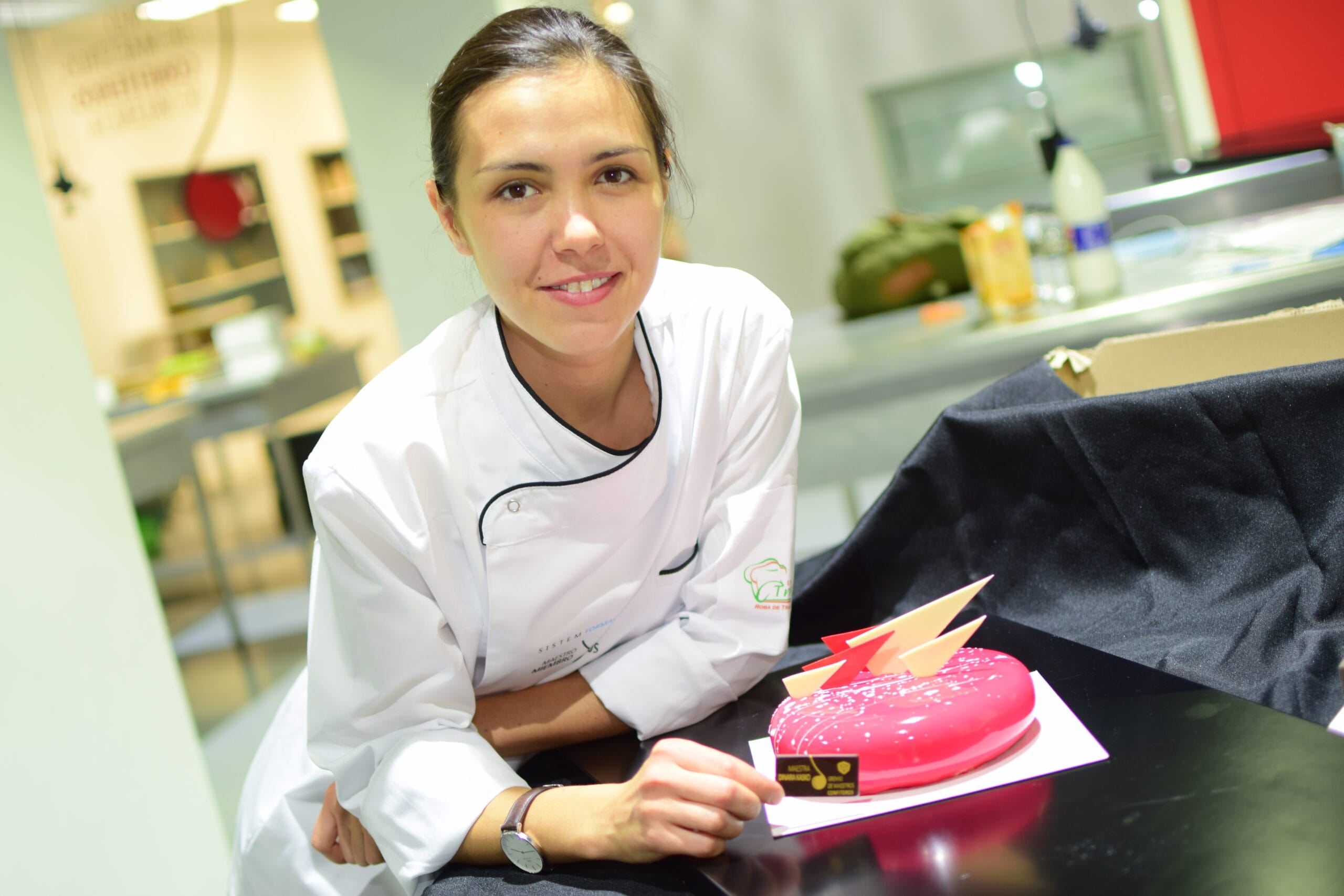 Dinara Kasko junto al pastel de fresa y coco durante una formación profesional
